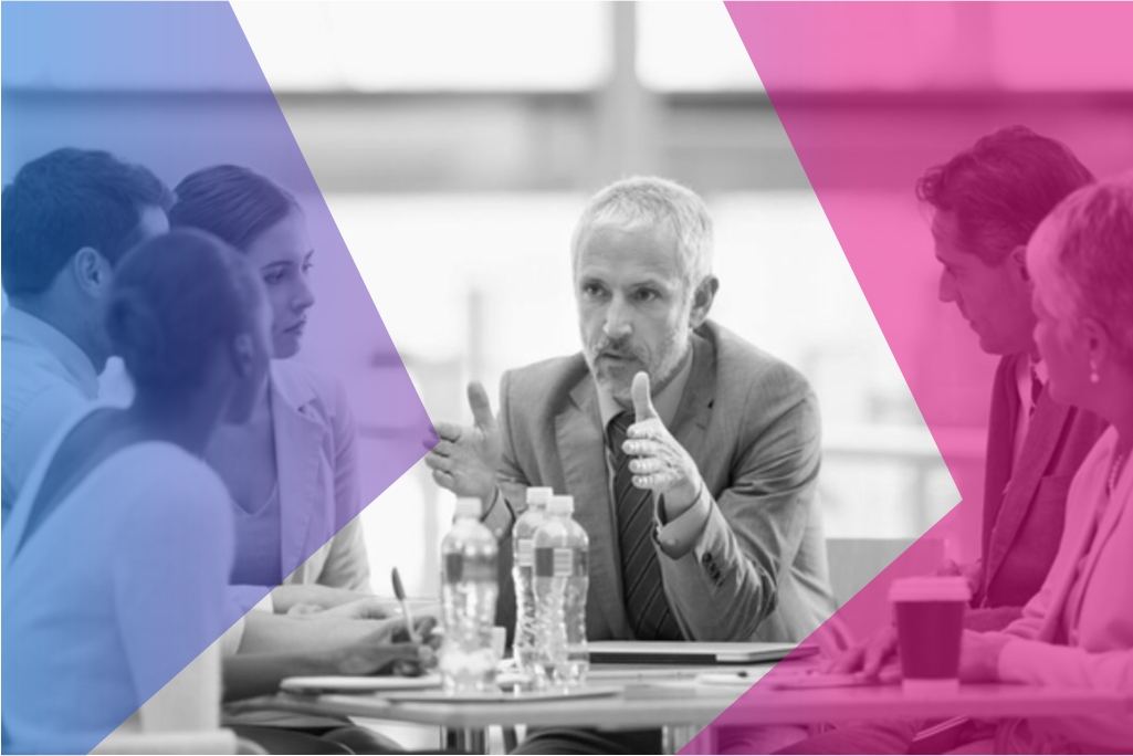 A Chief Operating Officer discussing operations with a team of people at a boardroom table.